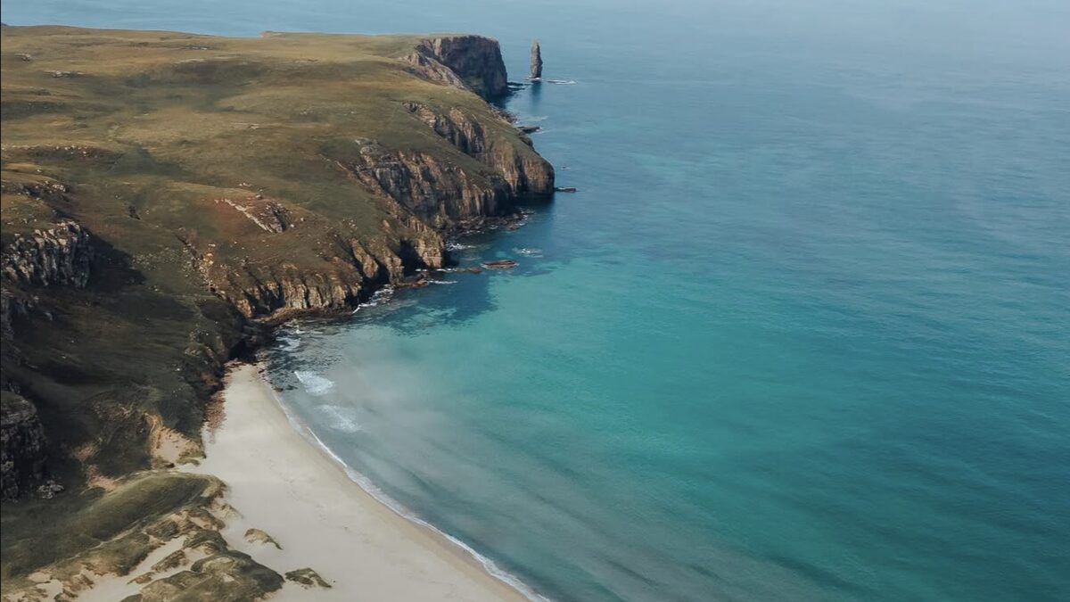Sandwood Bay with its long empty beach and the Am Buachaille sea stack at the south end, conveying Atlantic remoteness