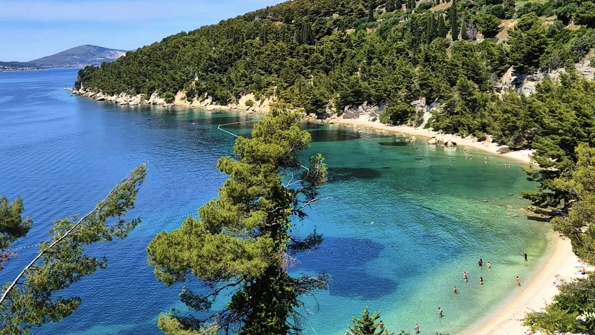 Kasjuni Beach at the southern edge of Marjan Hill in Split, a pebble beach backed by pine forest with clear water
