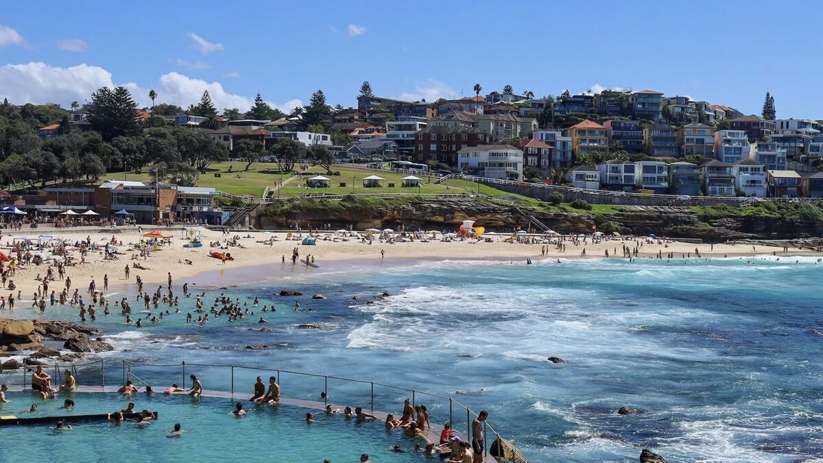 Bronte Beach in Sydney, the ocean rock pool full of swimmers at the southern end, with the surf beach and a grassy park rising to houses behind