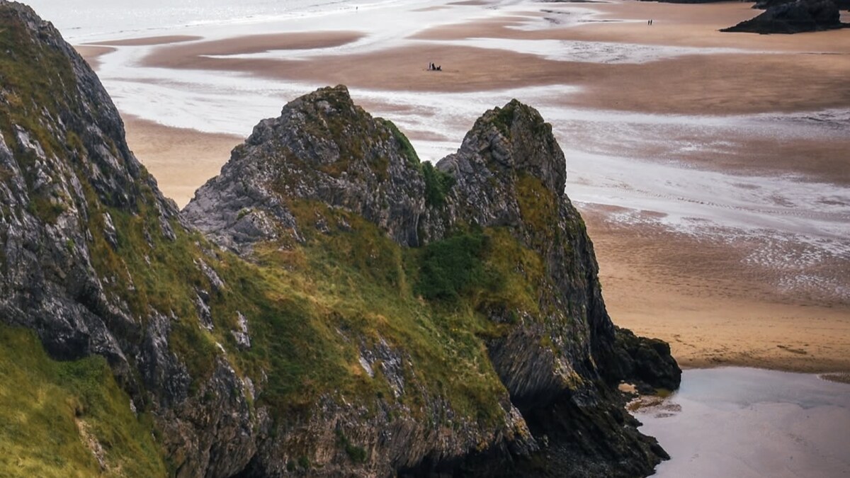 Three Cliffs Bay on the Gower from the cliff path, the limestone crags above the wide tidal sand with the estuary winding across it