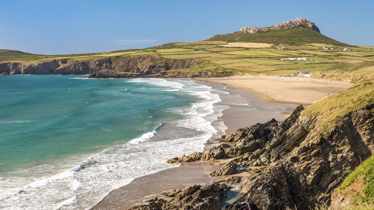 Whitesands Bay near St Davids in Pembrokeshire, Atlantic surf rolling onto the sand below the conical hill of Carn Llidi