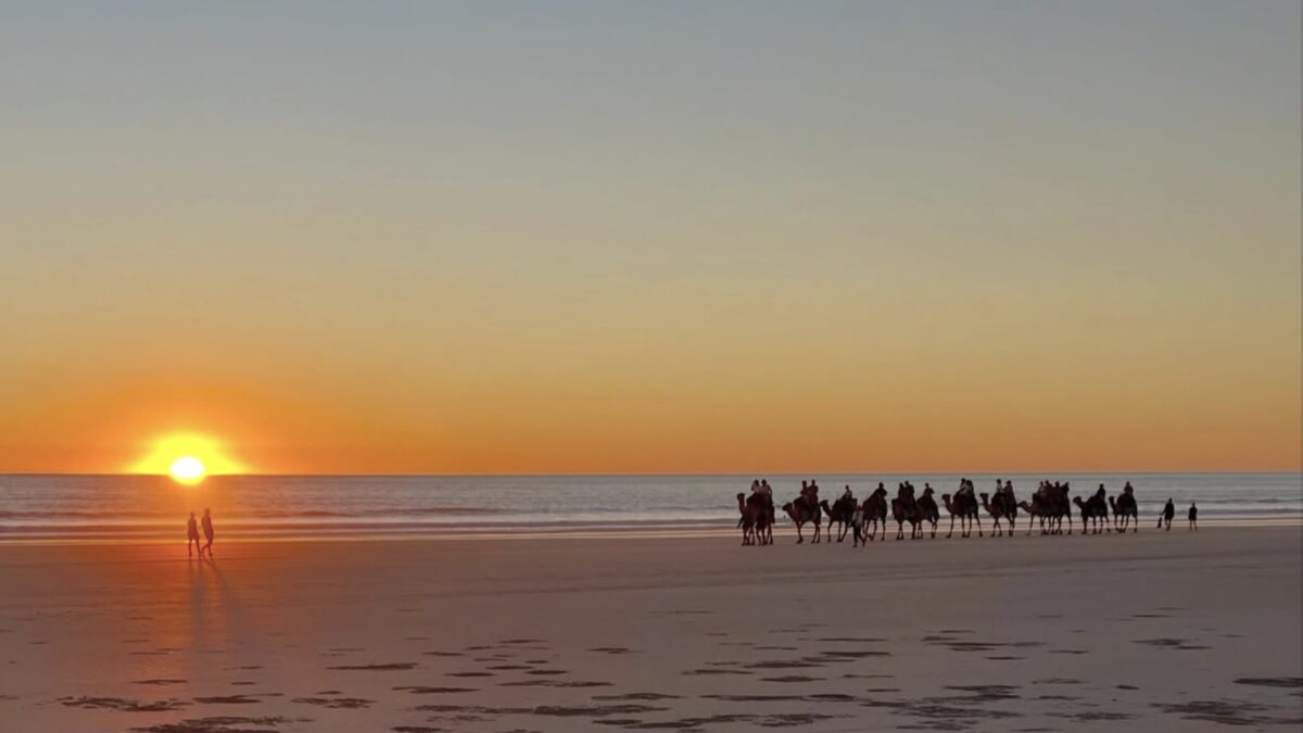 Camel train silhouettes on Cable Beach Broome at sunset against a red Indian Ocean sky