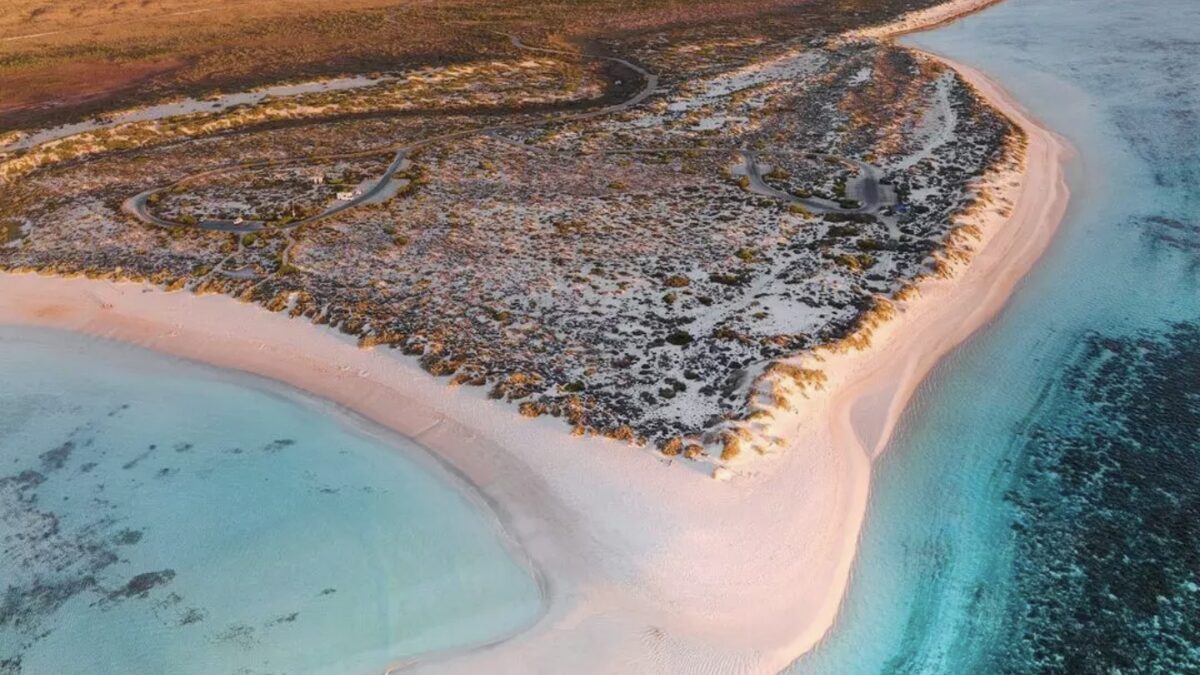 Aerial of Turquoise Bay near Exmouth at sunset, the turquoise lagoon beside the Ningaloo reef line with the low scrub of Cape Range behind