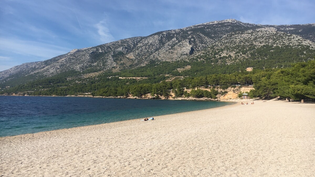 The long pebble beach at Bol on Brac, backed by pine forest and the bare grey slopes of Vidova Gora, the highest peak of the Adriatic islands