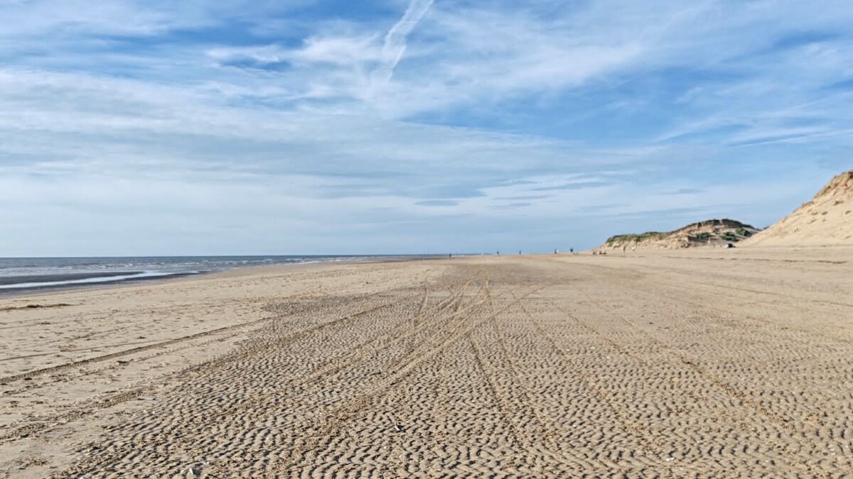 The vast ribbed sand of Formby beach at low tide, with the high dunes rising to the right