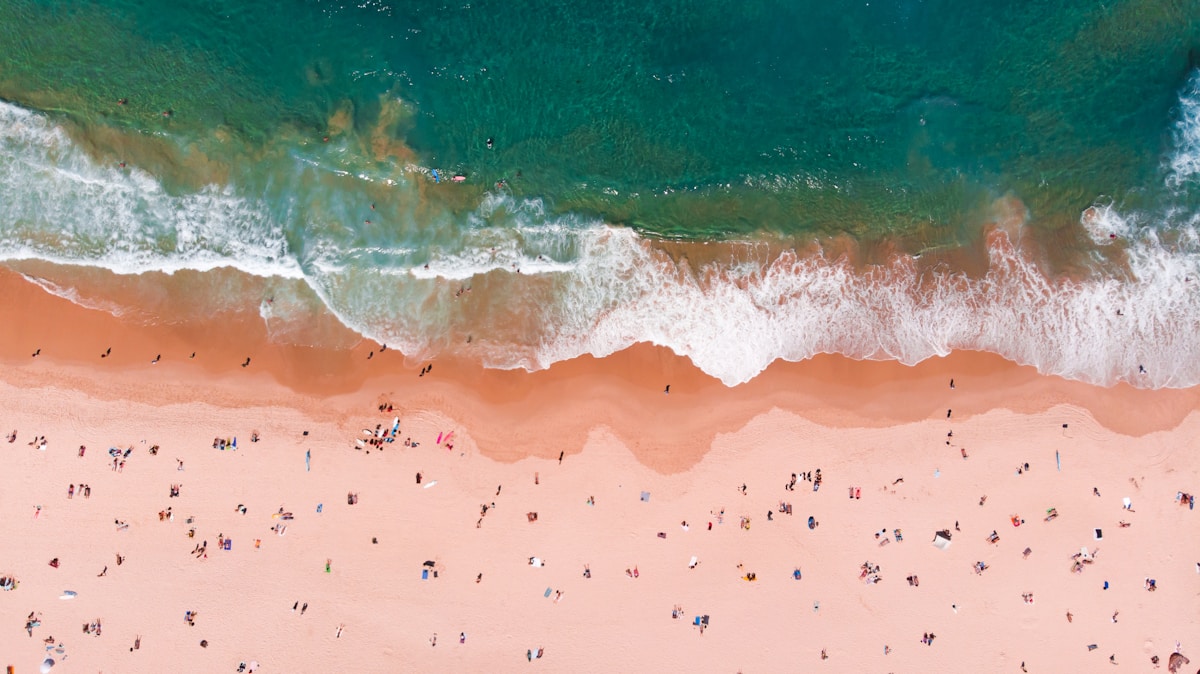 Aerial view of a crowded beach with hundreds of sunbathers and gentle waves