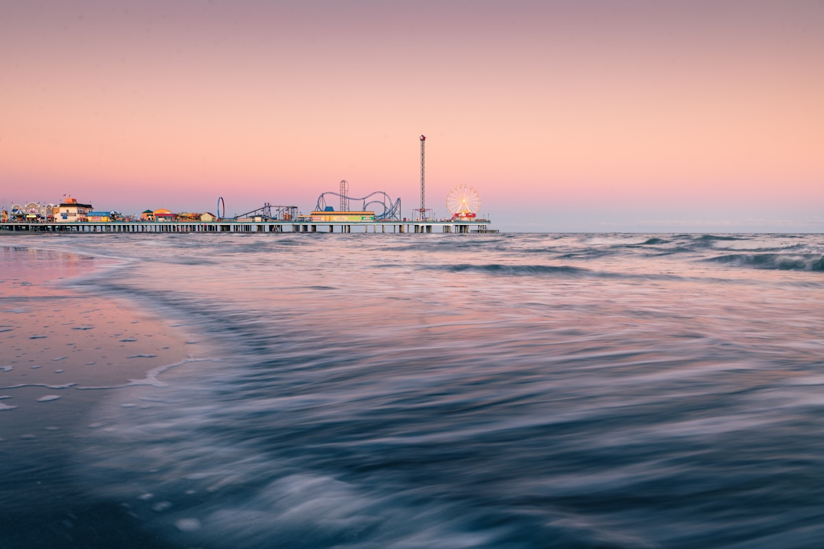 Galveston Pleasure Pier at sunset with waves in the foreground