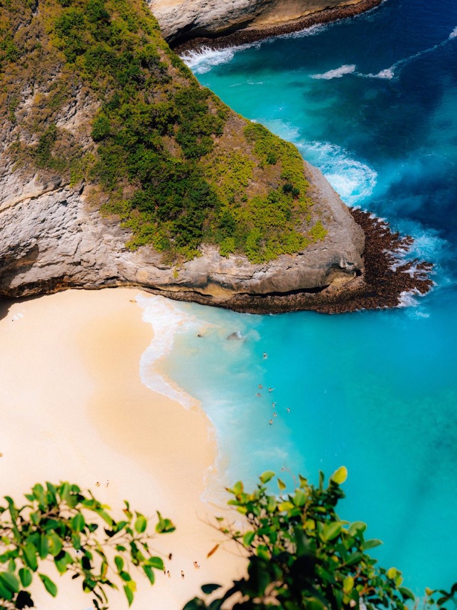 Aerial view of a hidden beach cove with turquoise water surrounded by rocky cliffs