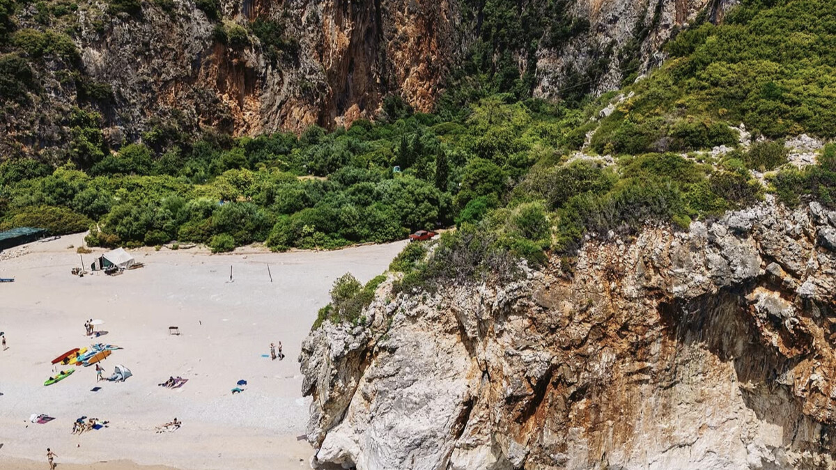 Gjipe beach on the Albanian Riviera, a white pebble cove at the mouth of a dramatic canyon with kayaks pulled up on the shore