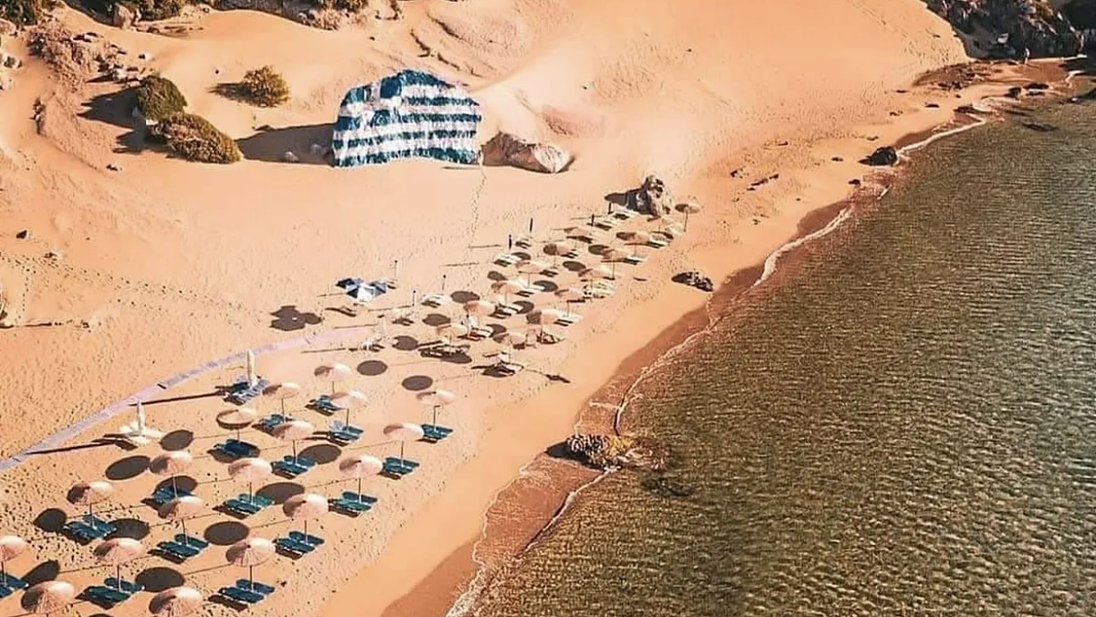Tsampika beach on Rhodes, golden sand and clear shallow turquoise water with the monastery hill rising at the northern end