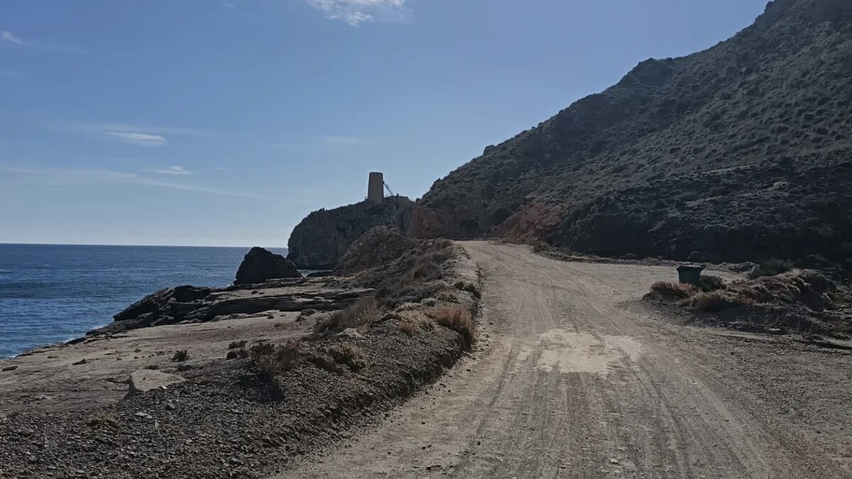 The rocky shore and dirt track at Macenas south of Mojacar, with the eighteenth-century Torre de Macenas watchtower on the headland ahead
