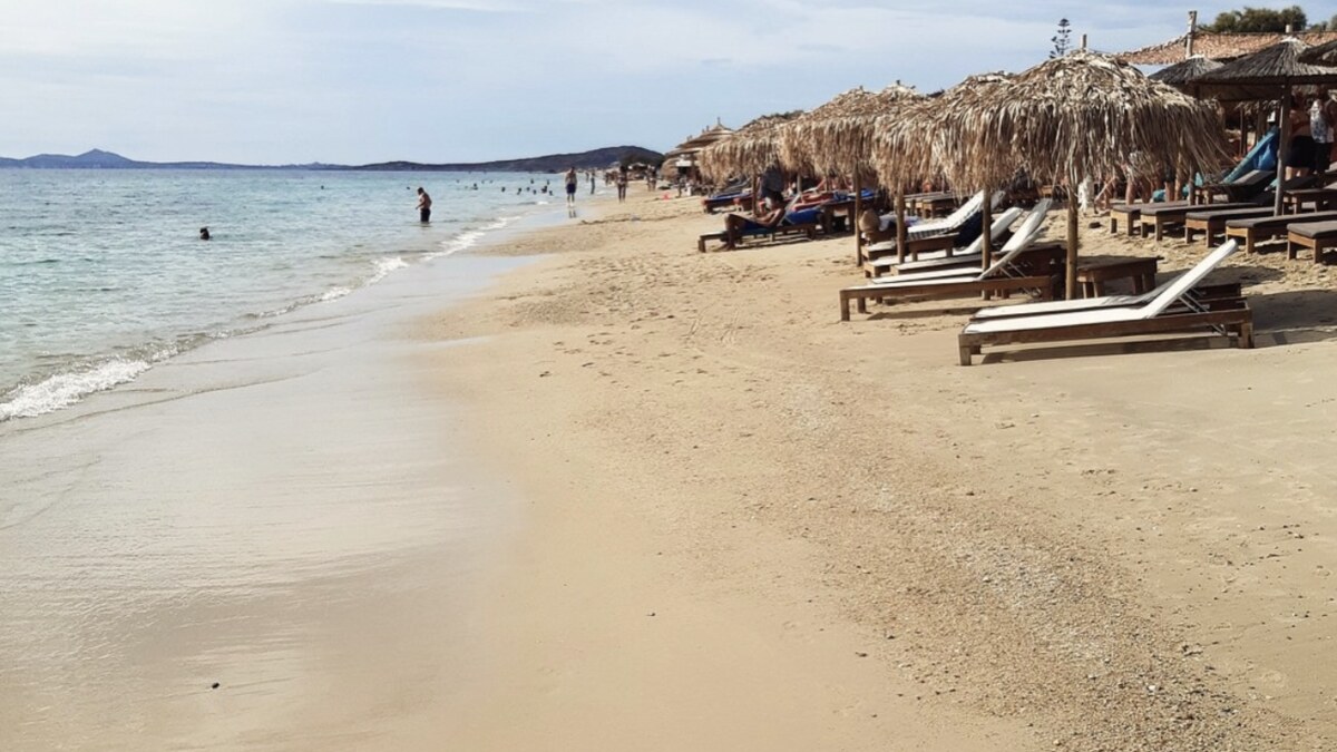 Plaka beach on Naxos, a long stretch of soft pale sand and clear shallow water running toward distant hills