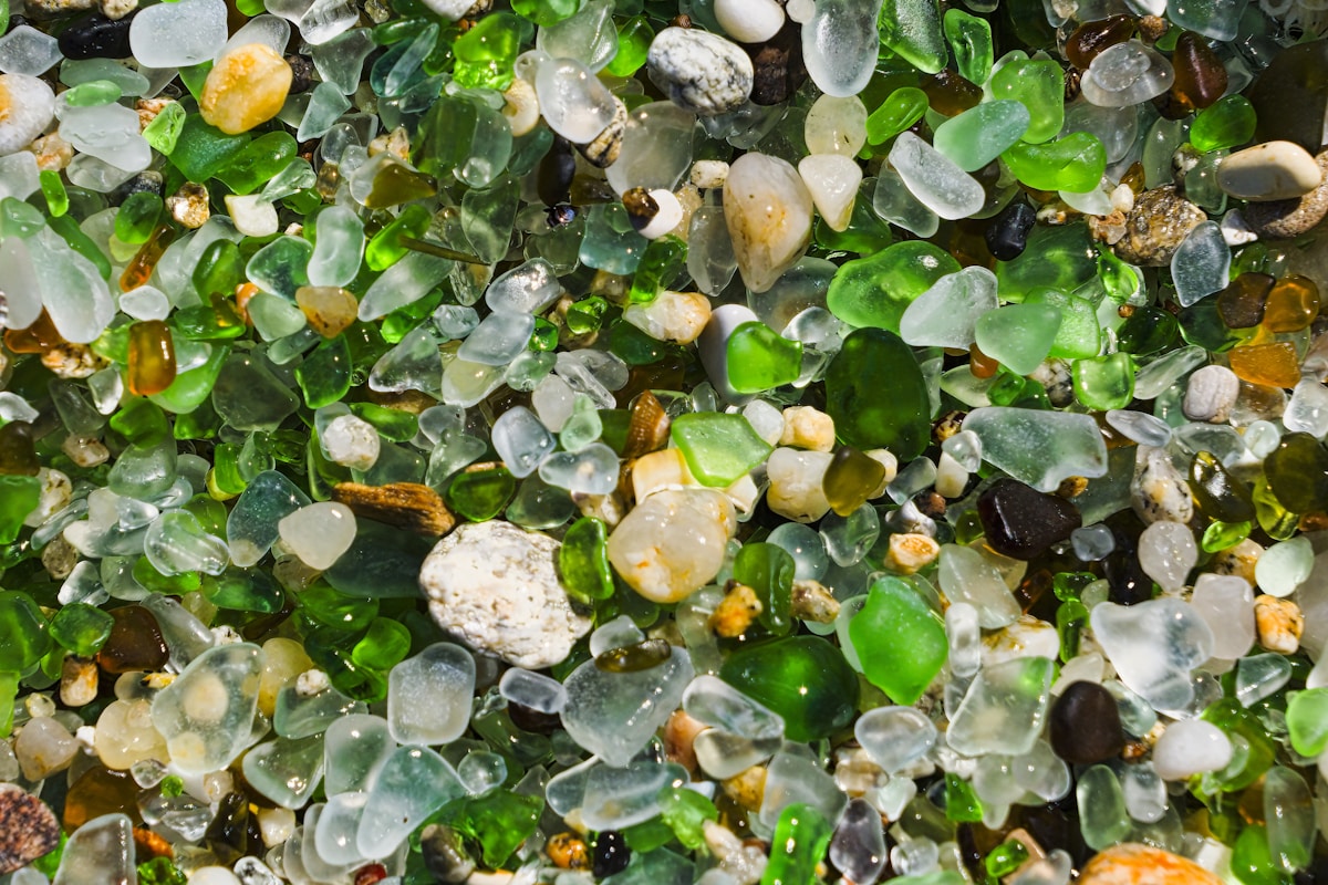 Colourful pieces of frosted sea glass in greens, whites and ambers collected on a pebble beach