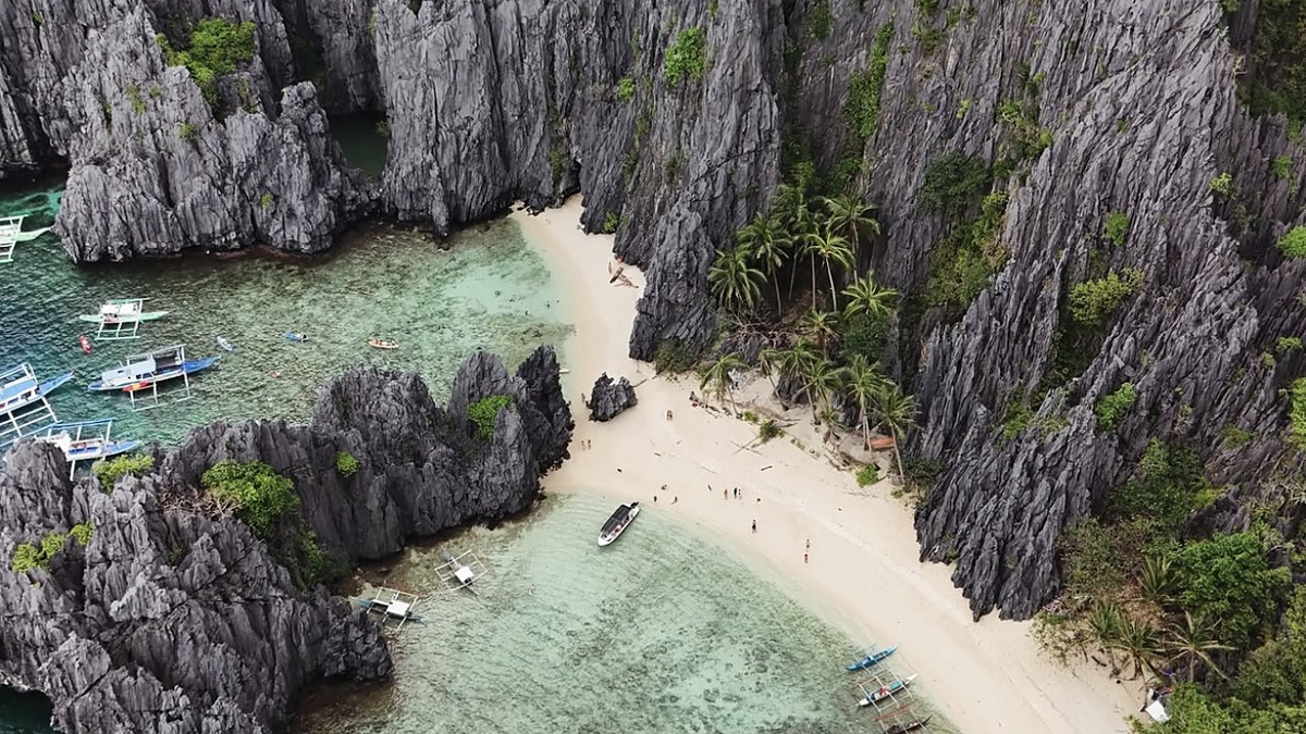 A hidden white-sand beach inside a limestone karst lagoon in the Bacuit Archipelago near El Nido, Philippines